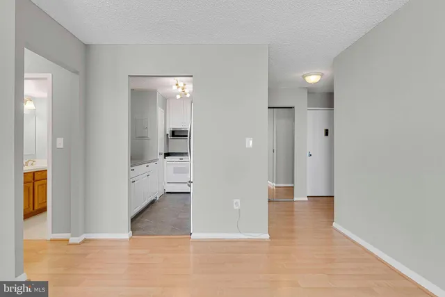 a view of a hallway with wooden floor and a bathroom