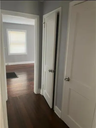 an empty room with wooden floor closet and windows