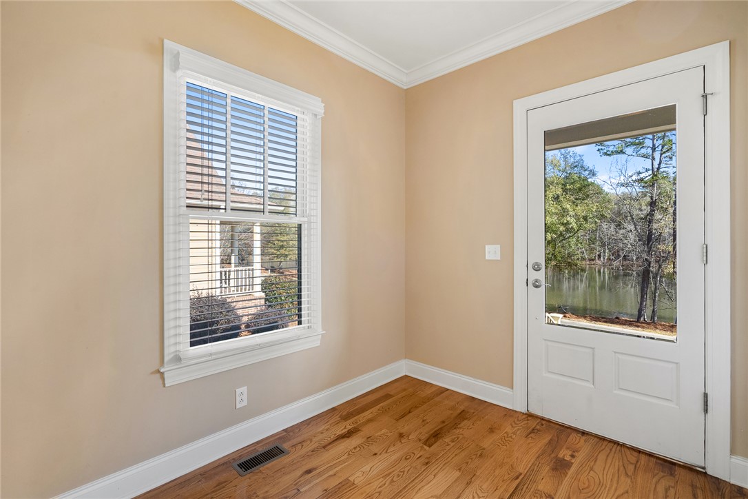 16 Oleander Drive Anderson, SC 29621 - Photo 5 of 37 Hardwood floors and crisp crown molding create a refined atmosphere, with a glass-paneled door opening to tranquil water views.