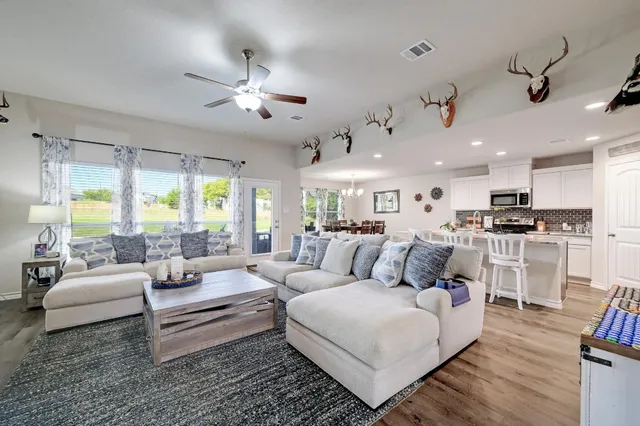 a kitchen with stainless steel appliances kitchen island granite countertop a refrigerator a stove top oven a sink dishwasher and white appliances with wooden floor