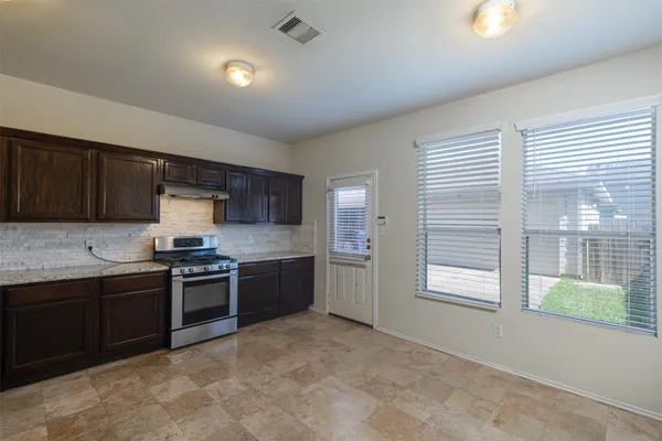 a large kitchen with stainless steel appliances granite countertop a stove sink and cabinets