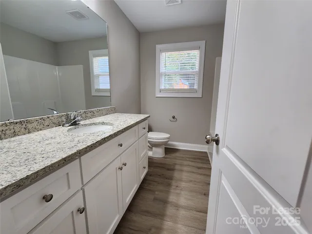 a bathroom with a granite countertop sink mirror and toilet