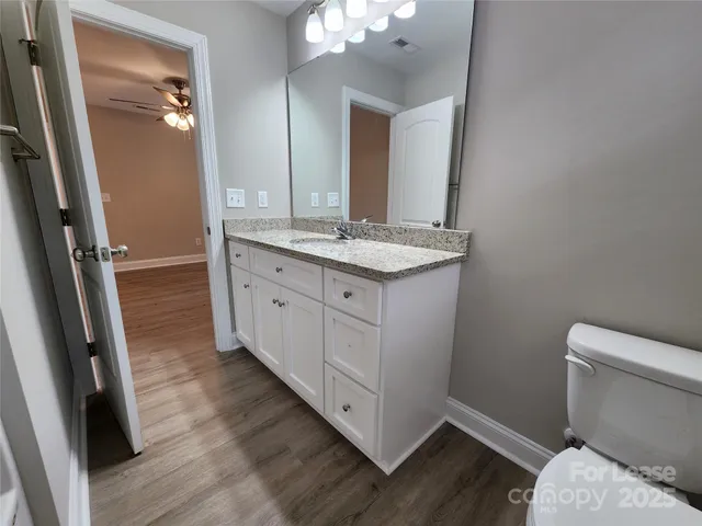 a bathroom with a granite countertop toilet sink and mirror