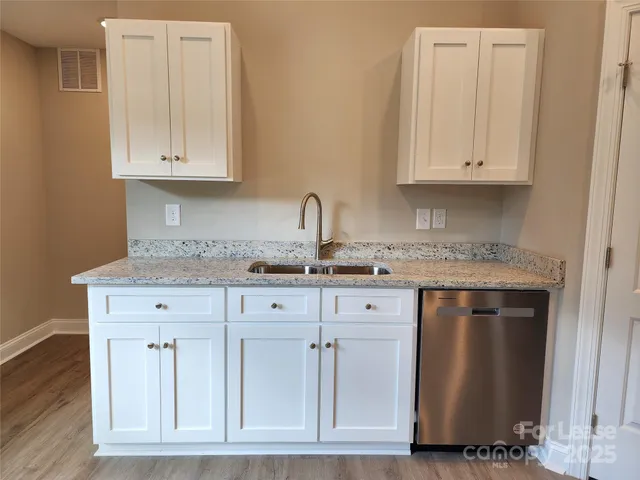 a kitchen with granite countertop white cabinets and sink