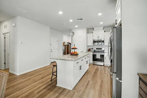 a kitchen with granite countertop a refrigerator stove top oven and sink