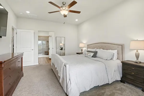 a spacious bedroom with a large bed and a chandelier