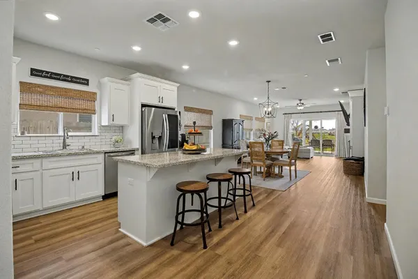 a kitchen with stainless steel appliances a dining table chairs stove refrigerator and cabinets