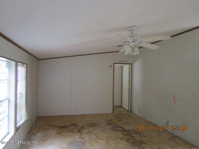 45072 Bismark Road Callahan, FL 32011 - Photo 6 of 39 an empty room with a chandelier fan and windows