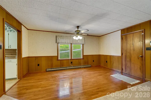 a view of an empty room with wooden floor and a window