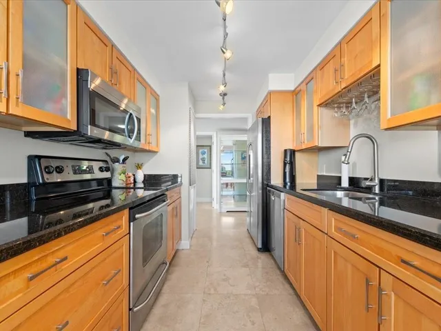 a kitchen with stainless steel appliances granite countertop a sink a stove and a refrigerator
