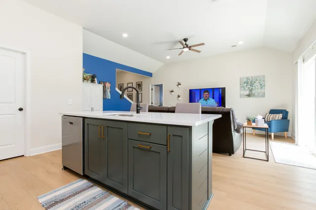 a kitchen with stainless steel appliances kitchen island granite countertop a sink cabinets and wooden floor