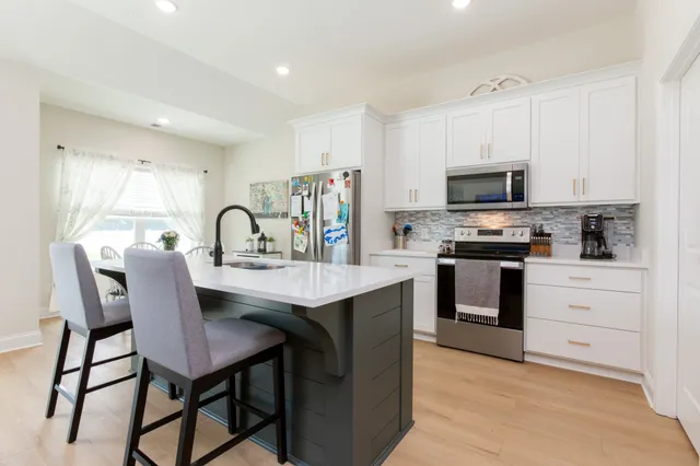 a kitchen with stainless steel appliances kitchen island granite countertop a table chairs microwave and sink