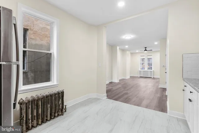 a view of a hallway to a bedroom with wooden floor and windows