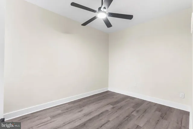 an empty room with wooden floor ceiling fan and window