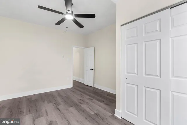 an empty room with wooden floor ceiling fan