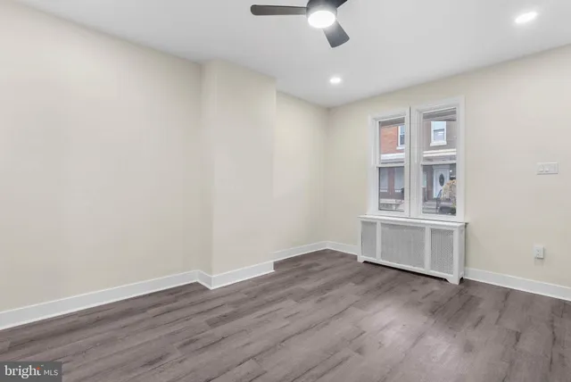 a view of an empty room with a window and wooden floor