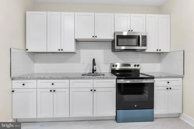 a kitchen with white cabinets and stainless steel appliances