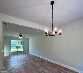 a view of a room with a chandelier fan and wooden floor