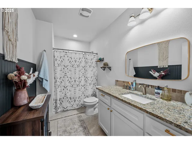 a bathroom with a granite countertop sink a toilet and a mirror