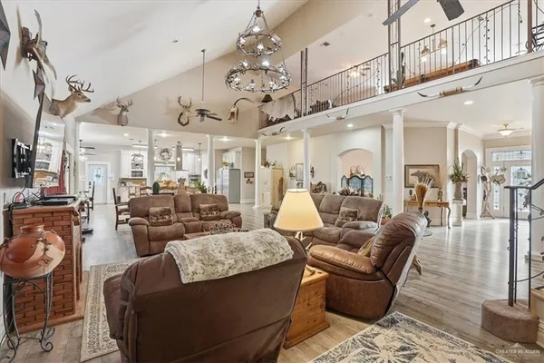 a living room with furniture a chandelier and wooden floor