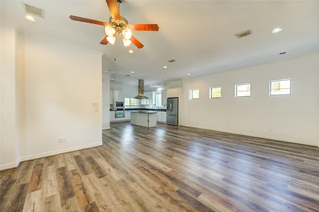 a view of kitchen and empty room with wooden floor