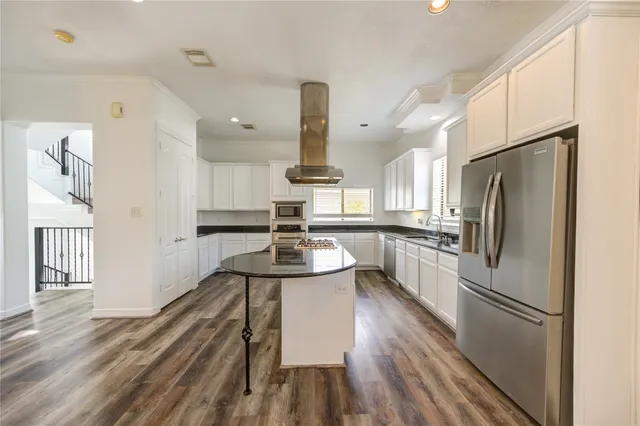 a kitchen with kitchen island stainless steel appliances a sink and wooden floor
