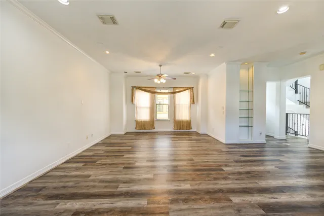 a view of an empty room with window and wooden floor