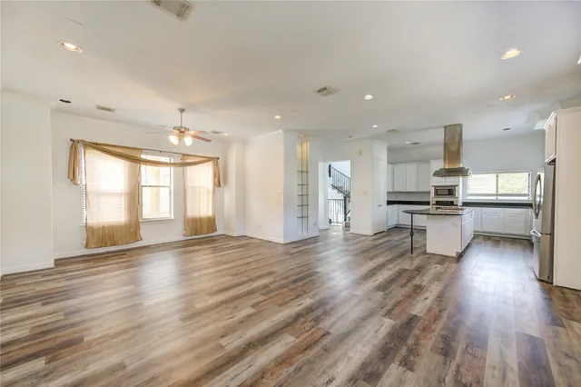 a view of kitchen with kitchen island wooden floor and stainless steel appliances