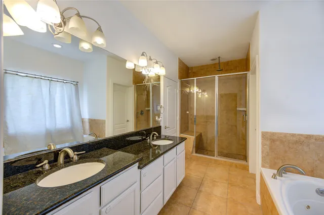 a spacious bathroom with a granite countertop double vanity sink a mirror and a shower
