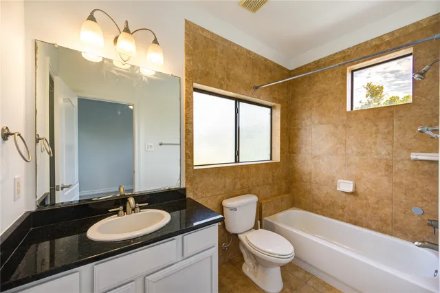 a bathroom with a granite countertop sink mirror toilet and bathtub