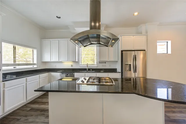 a kitchen with granite countertop a refrigerator a stove a sink dishwasher and cabinets with wooden floor