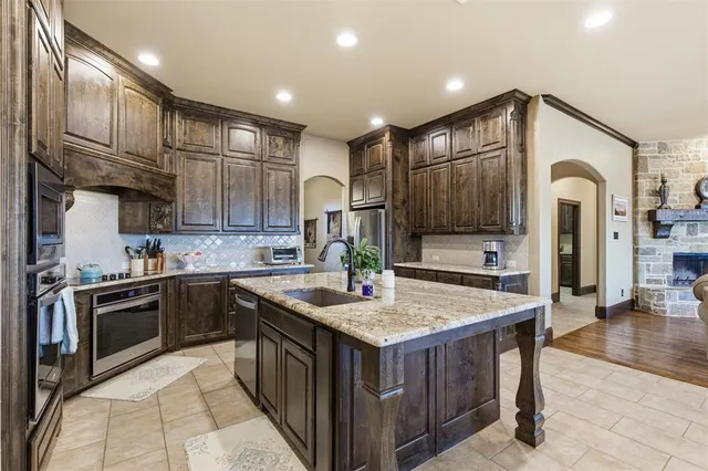 a kitchen with stainless steel appliances granite countertop a sink and a refrigerator