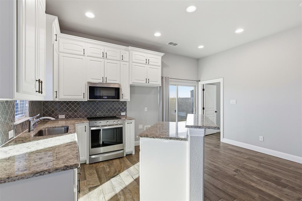 6298 Belz Road Sanger, TX 76266 - Photo 24 of 40 a kitchen with kitchen island granite countertop a sink cabinets and stainless steel appliances