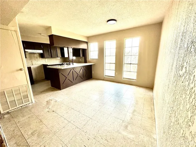 a large room with kitchen island granite countertop a sink a counter top space and stainless steel appliances
