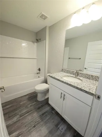 a bathroom with a granite countertop sink a toilet and bathtub