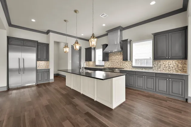 a large kitchen with granite countertop a large counter top space a sink stainless steel appliances and cabinets