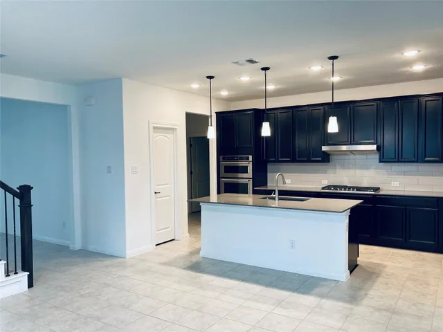 a large kitchen with stainless steel appliances granite countertop a stove a sink and a refrigerator