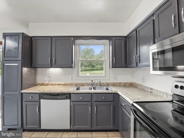 an empty room with a chandelier fan and windows