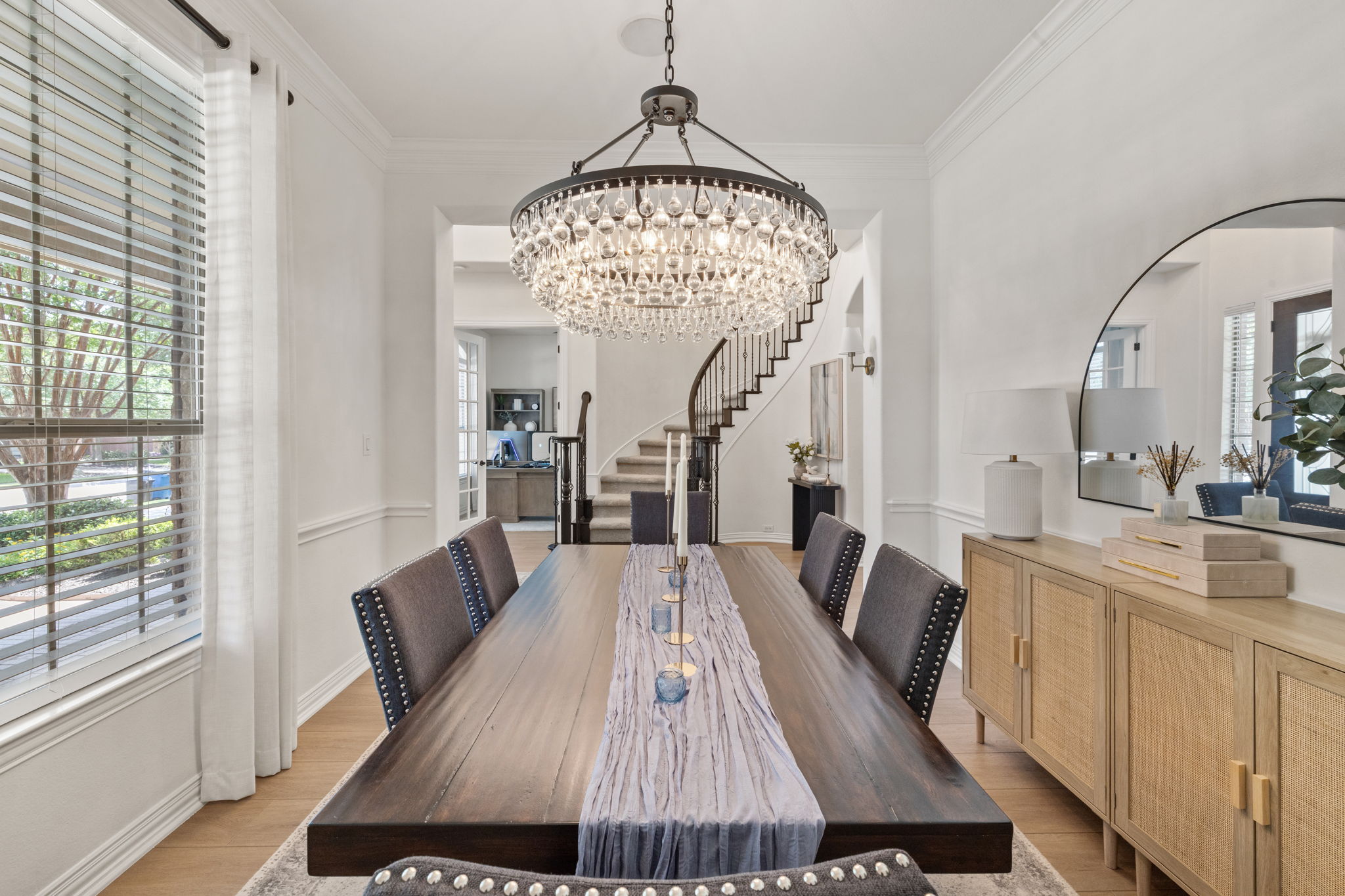 1124 Castle Path Round Rock, TX 78681 - Photo 9 of 40 A grand crystal chandelier illuminates this elegant dining space with light wood flooring and a curved staircase.