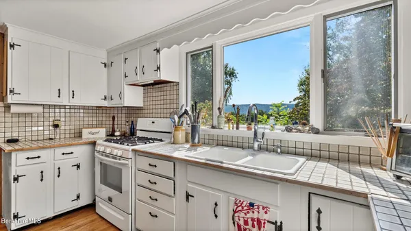 a kitchen with stainless steel appliances granite countertop a stove top oven a sink dishwasher and cabinets with wooden floor