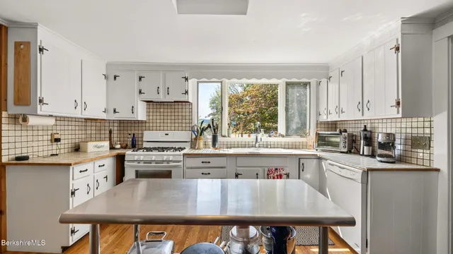 a kitchen filled with white cabinets and wooden floor