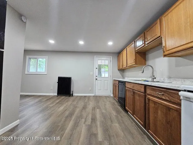 a view of kitchen with sink wooden cabinets and entryway