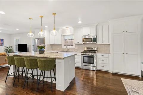 a kitchen with stainless steel appliances kitchen island granite countertop a stove a sink and a refrigerator