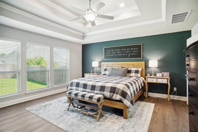 a bedroom with a bed a dresser and a large window