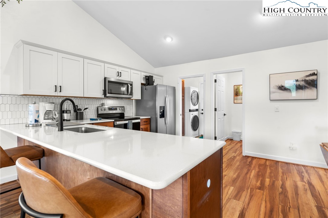 429 Townhomes Place, Unit 18 Boone, NC 28607 - Photo 6 of 25 a kitchen with stainless steel appliances a stove a refrigerator a sink a oven with white cabinets and wooden floor