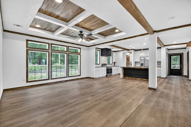 a view of a livingroom with wooden floor and a kitchen
