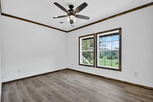 an empty room with wooden floor and windows