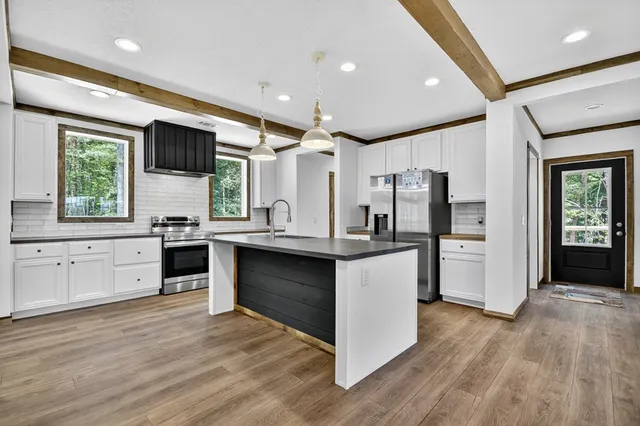 a kitchen with stainless steel appliances kitchen island granite countertop a stove a sink and a refrigerator