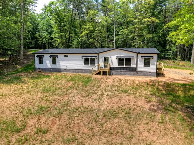 a front view of a house with yard and large trees