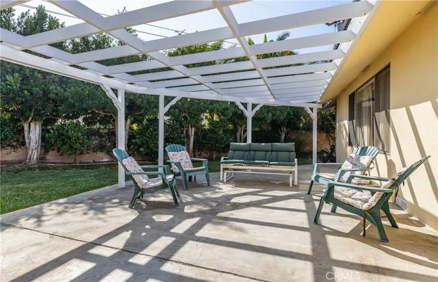 a view of a patio with table and chairs under an umbrella with large trees